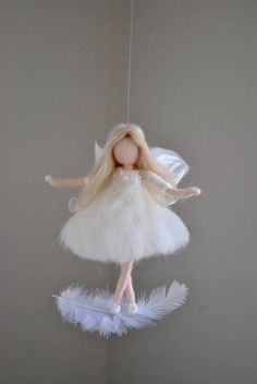 a doll hanging from a string with white feathers