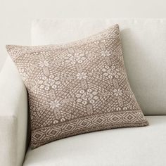 a white couch with a brown pillow on it's back and the cushion is made out of fabric