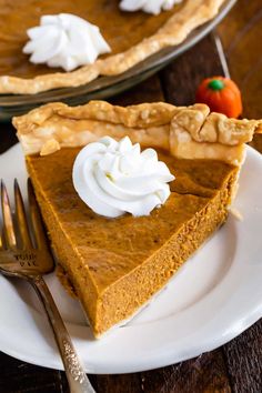 a slice of pumpkin pie on a white plate with a fork next to the pie