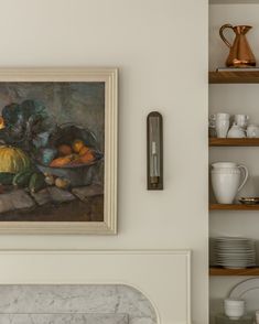 a painting hanging on the wall next to a shelf filled with plates and bowls in front of a fireplace