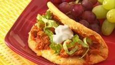 a red plate topped with a sandwich next to grapes