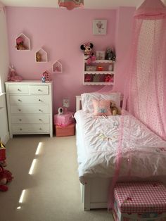 a child's bedroom with pink walls and white furniture, including a princess bed