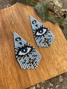 a pair of blue beaded earrings sitting on top of a wooden table next to a plant