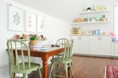 a dining room table with green chairs and pictures on the wall above it, along with other furniture