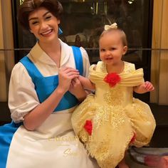 a woman holding a baby wearing a princess costume