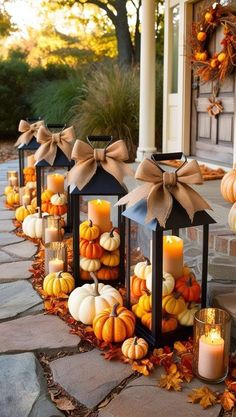 pumpkins and candles are lined up in front of a house with bows on them