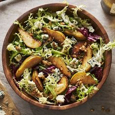 a wooden bowl filled with salad next to two cups of tea and spoons on a table