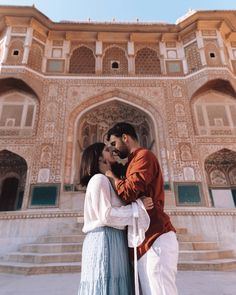 a man and woman are standing in front of a building with an ornate archways