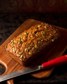 a loaf of bread sitting on top of a wooden cutting board next to a knife