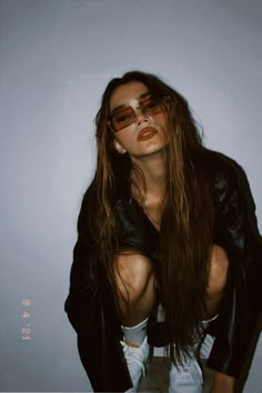 a woman with long hair and sunglasses sitting on the floor