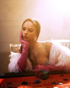 a woman sitting at a roulejack table with her hand on her face and holding a dice