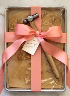 a cake in a pan with a pink ribbon tied around it and a wooden spatula