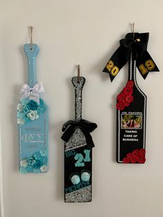 three tags are hanging on the wall next to each other with flowers and ribbons around them