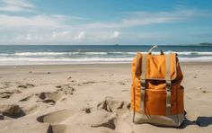 a yellow backpack sitting on top of a sandy beach