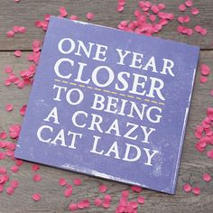 a sign that says one year closer to being a crazy cat lady with pink confetti scattered around it