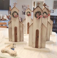 three wooden houses with wreaths on them sitting on a table