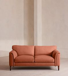 an orange couch sitting on top of a hard wood floor next to a white wall