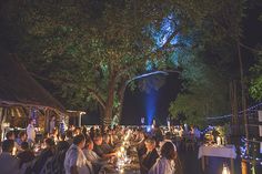 a group of people sitting around a table with candles in front of them at night