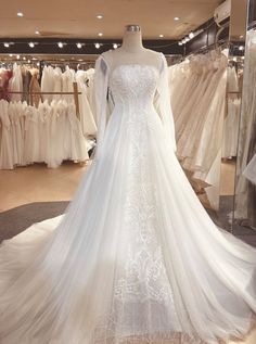 a white wedding dress on display in a store with lots of gowns behind it