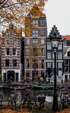 several bicycles parked next to a lamp post in front of some buildings on the water