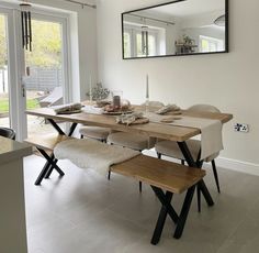 a dining room table and bench with mirrors on the wall