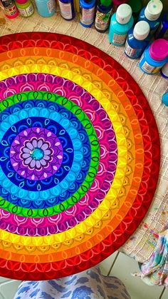 a colorful circular rug on top of a wooden floor next to paint bottles and brushes