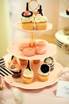 three tiered cupcake display with pink frosting and black decorations on each tier