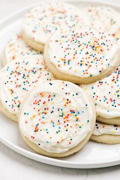 white frosted cookies with sprinkles on a plate