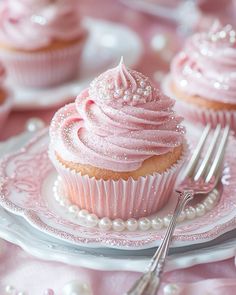 cupcakes with pink frosting and sprinkles are on the plate