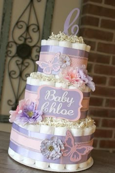 a three tiered cake with flowers and butterflies on the top is sitting on a table