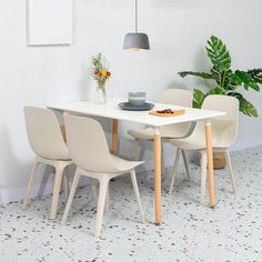 a white table with four chairs and a potted plant in the corner next to it