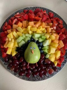 a fruit platter with a face made out of apples, grapes, strawberries and pears