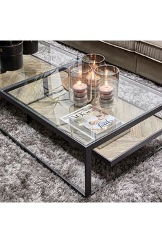 a glass coffee table with candles on top