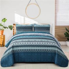 a bed with blue and white bedspread in a room next to potted plants