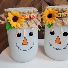 two painted mason jars decorated with sunflowers and burlocks are sitting on a table