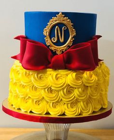 a yellow and blue cake with red ribbon on top