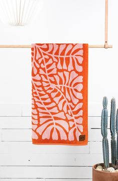 an orange and white towel hanging on a wall next to a potted cacti