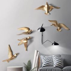 a living room filled with furniture and lots of gold birds on the wall above it