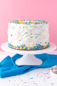 a white cake with sprinkles on it sitting on top of a table