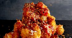 a pile of fried food sitting on top of a wooden table next to a black wall