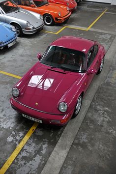 there are many different colored cars parked in the parking lot, and one is red