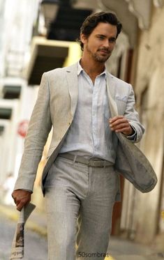 a man is walking down the street with an umbrella in his hand and wearing a suit