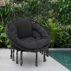 a black hanging chair next to a pool