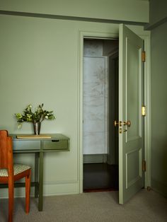 a green room with a desk and chair next to a door that leads to another room