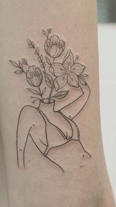 a woman's arm with a tattoo on it that has flowers in the vase