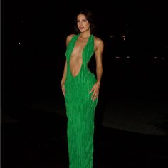 a woman in a green dress posing for the camera at night with her hands on her hips