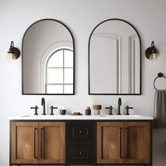 two mirrors are above the double sink vanity in this white and black bathroom with wood cabinetry