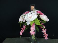 a vase filled with pink and white flowers sitting on top of a table next to a black wall