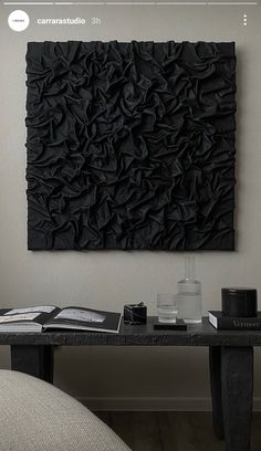 a black wall hanging on the side of a white wall next to a table and chair