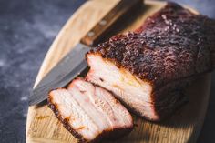 sliced pork on a cutting board with knife and fork next to it, ready to be eaten